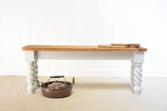 A pot sitting on top of a table next to a bench.